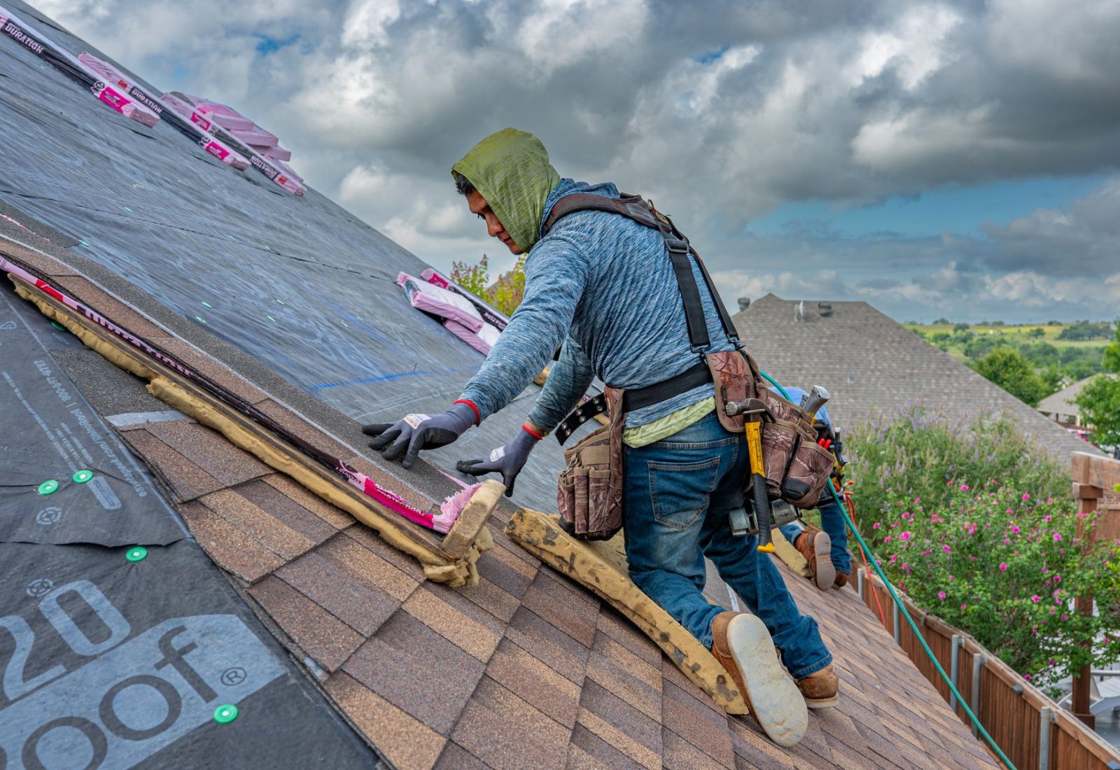 Dachdecker arbeitet konzentriert auf einem geneigten Dach unter Wolkenhimmel