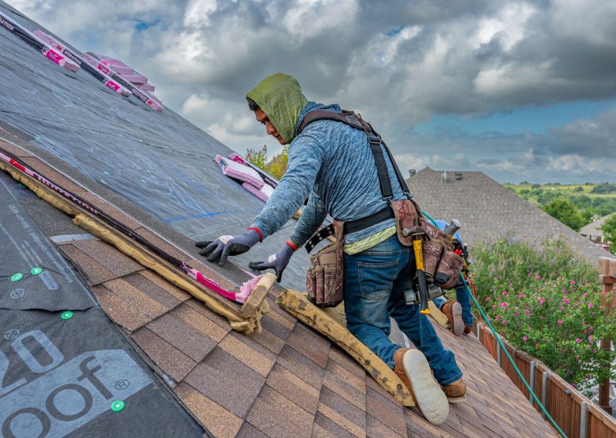 Dachdecker arbeitet konzentriert auf einem geneigten Dach unter Wolkenhimmel